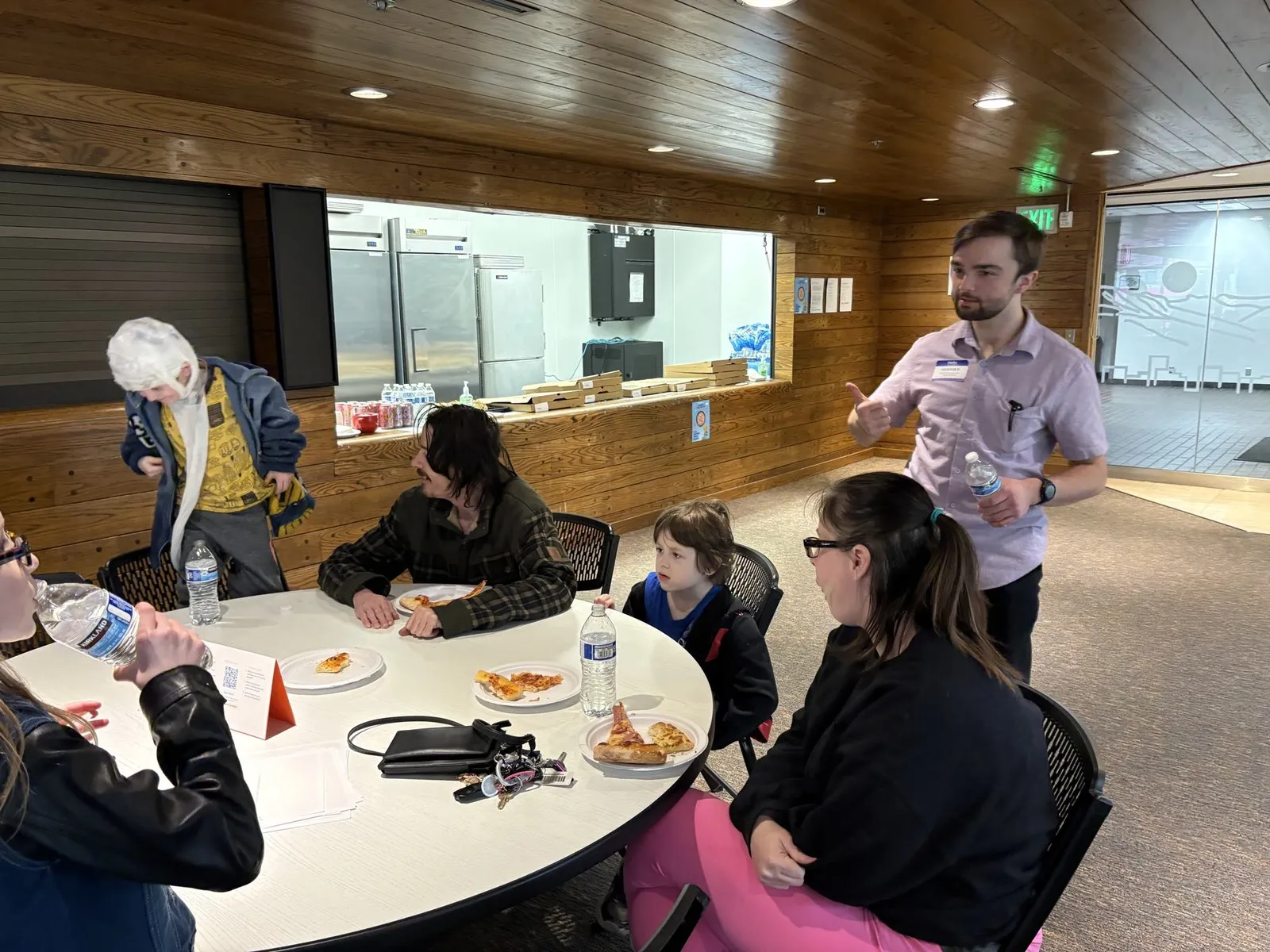 Attendees eating pizza together at Bitcoin Pizza Day in The Den, UAA